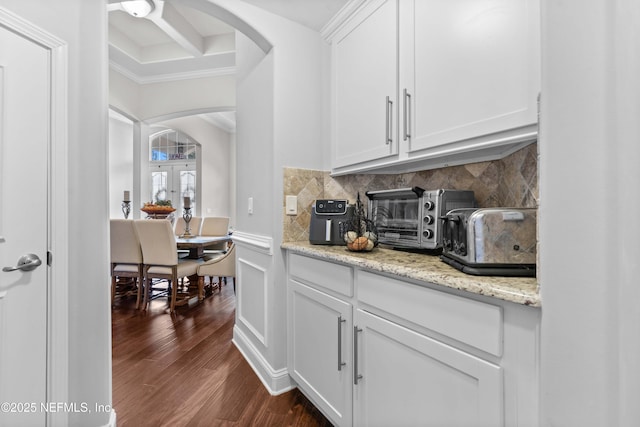 bar with dark hardwood / wood-style flooring, decorative backsplash, light stone countertops, and white cabinets