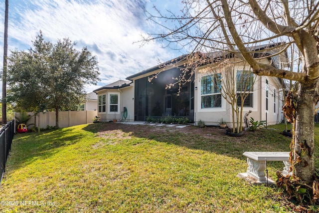 rear view of house with a yard and a sunroom