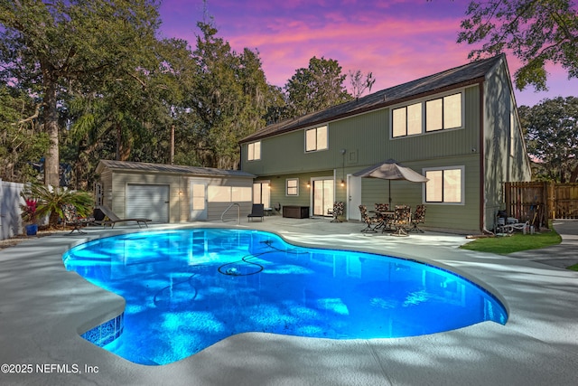 pool at dusk with a patio area and a shed