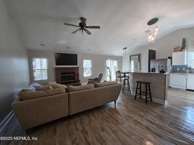 living room with dark hardwood / wood-style flooring, a fireplace, lofted ceiling, and ceiling fan