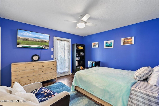 bedroom with ceiling fan, dark hardwood / wood-style floors, and a textured ceiling