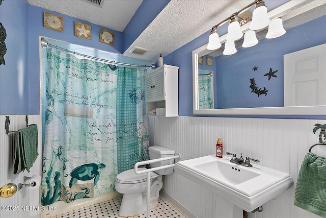 bathroom with walk in shower, toilet, sink, and a textured ceiling