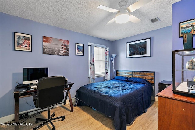 bedroom with ceiling fan, light hardwood / wood-style floors, and a textured ceiling