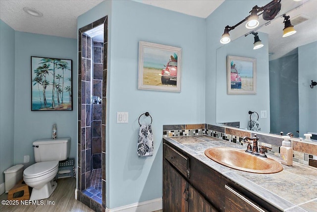 bathroom featuring toilet, wood-type flooring, a textured ceiling, vanity, and a shower with door