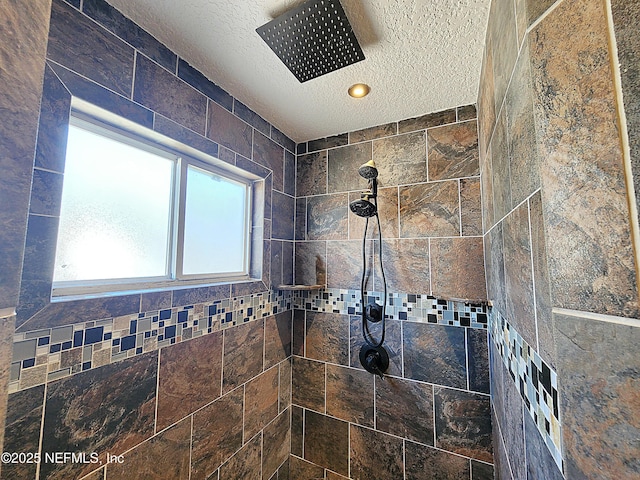 bathroom featuring a tile shower and a textured ceiling