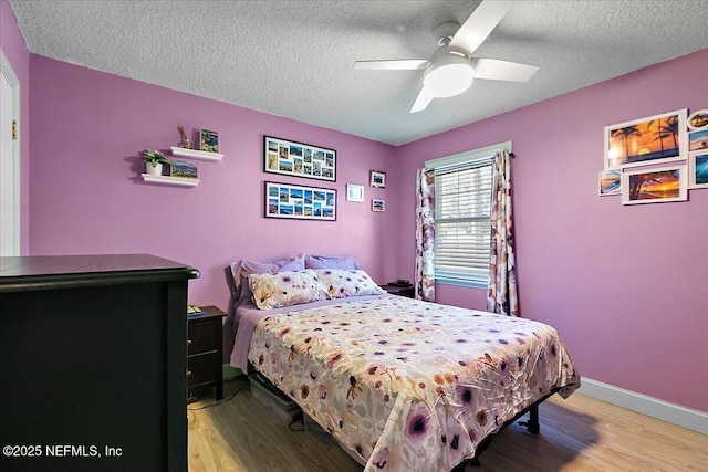 bedroom with ceiling fan, hardwood / wood-style floors, and a textured ceiling