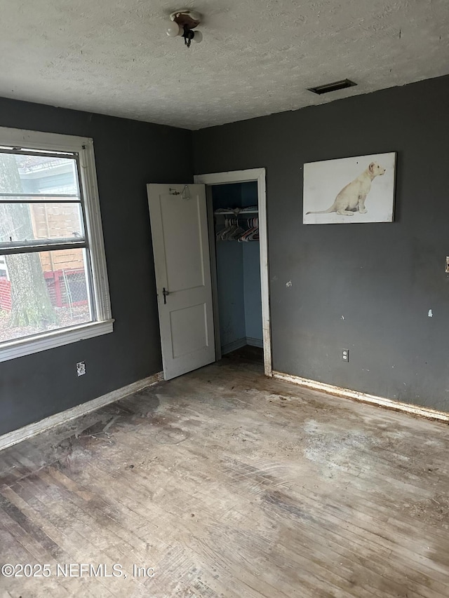 unfurnished bedroom featuring hardwood / wood-style floors, a closet, and a textured ceiling