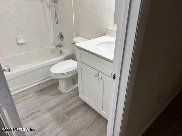 full bathroom with hardwood / wood-style flooring, vanity, toilet, and tiled shower / bath combo