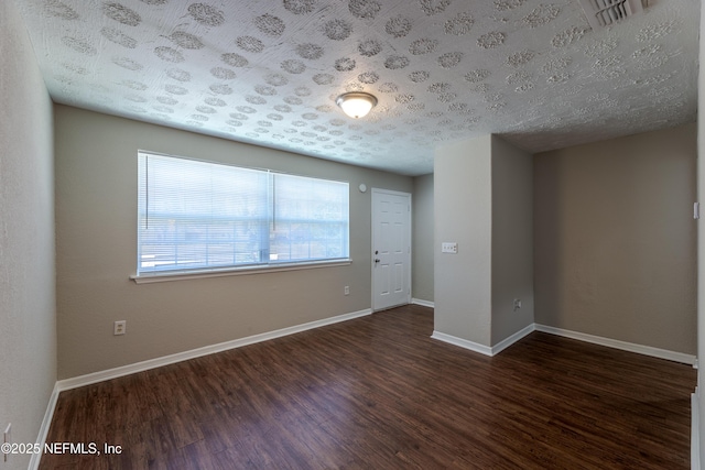 spare room featuring dark hardwood / wood-style floors and a textured ceiling