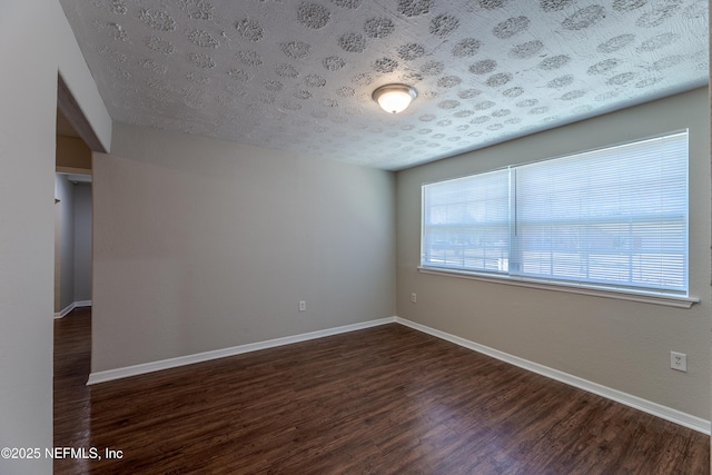 spare room with a textured ceiling and dark hardwood / wood-style flooring