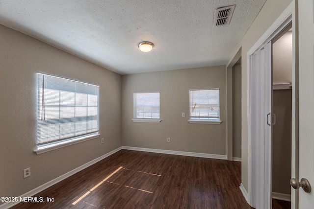 unfurnished bedroom with dark wood-type flooring and a textured ceiling