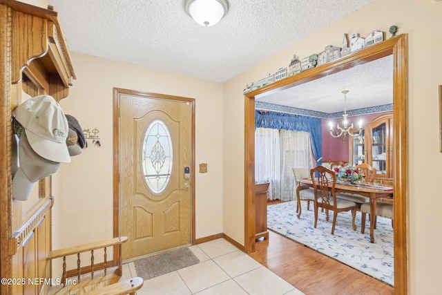 foyer entrance with a notable chandelier, light hardwood / wood-style flooring, and a textured ceiling