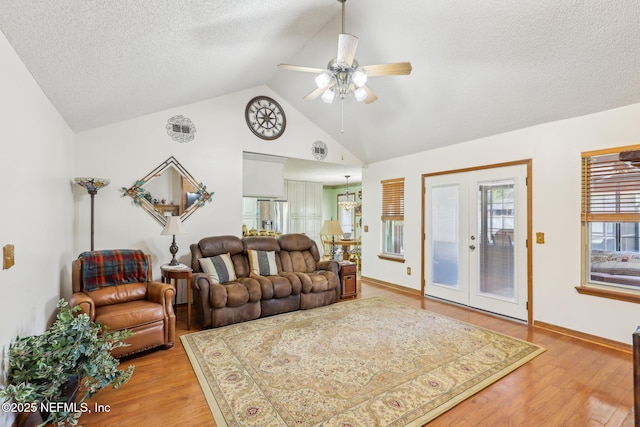 living room featuring ceiling fan, vaulted ceiling, a textured ceiling, and light wood-type flooring