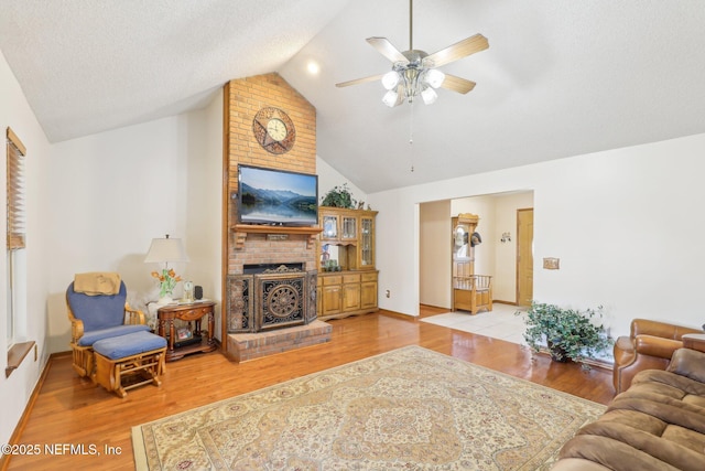 living room featuring ceiling fan, high vaulted ceiling, a textured ceiling, and light wood-type flooring