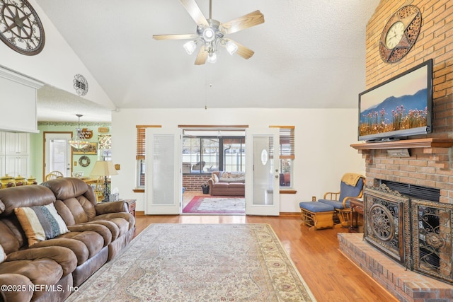 living room featuring high vaulted ceiling, a textured ceiling, light wood-type flooring, ceiling fan, and a fireplace