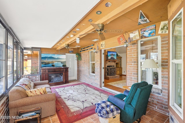 living room with beamed ceiling, ceiling fan, brick wall, and tile patterned flooring