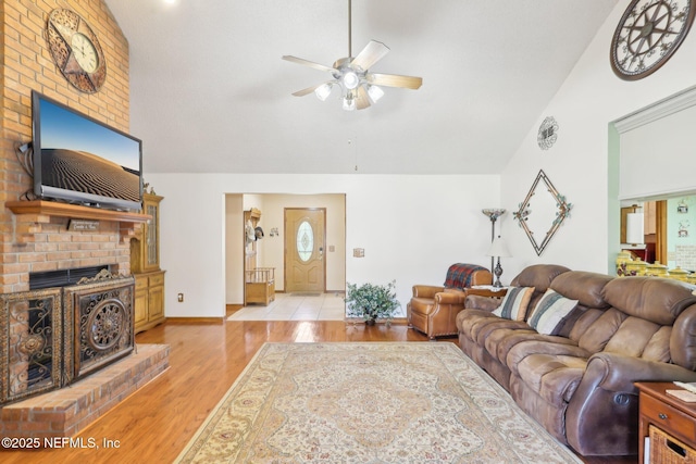 living room with ceiling fan, high vaulted ceiling, light hardwood / wood-style floors, and a brick fireplace