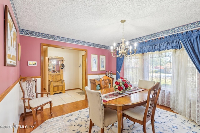 dining area with a textured ceiling, light hardwood / wood-style flooring, and a chandelier