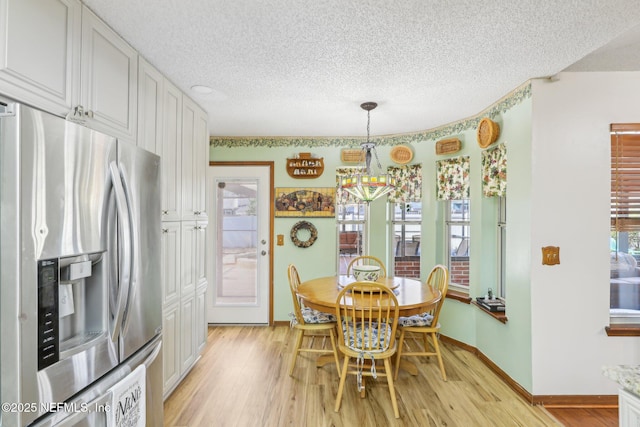 dining room with a notable chandelier, a textured ceiling, and light wood-type flooring