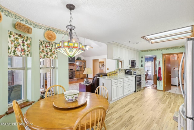 dining area with light hardwood / wood-style floors and a textured ceiling