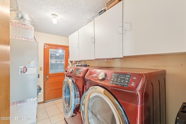 washroom with cabinets, light tile patterned flooring, a textured ceiling, and washer and clothes dryer