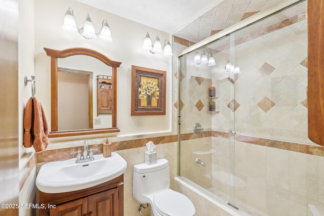 bathroom featuring an enclosed shower, vanity, tile walls, and toilet