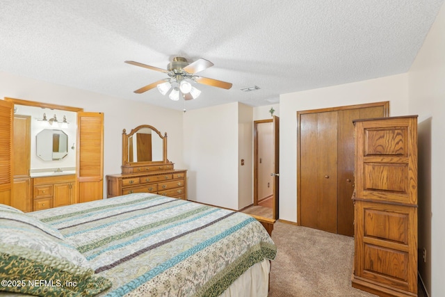 carpeted bedroom with ceiling fan, a closet, ensuite bathroom, and a textured ceiling