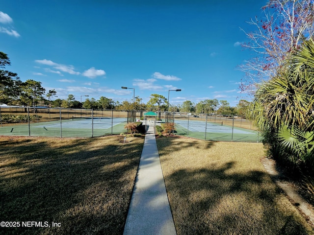 view of tennis court with a yard