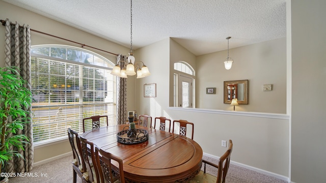 carpeted dining area featuring plenty of natural light, an inviting chandelier, and a textured ceiling