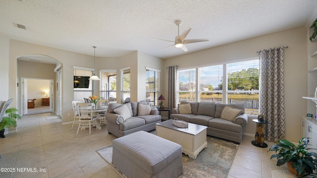 tiled living room featuring ceiling fan, a healthy amount of sunlight, and a textured ceiling