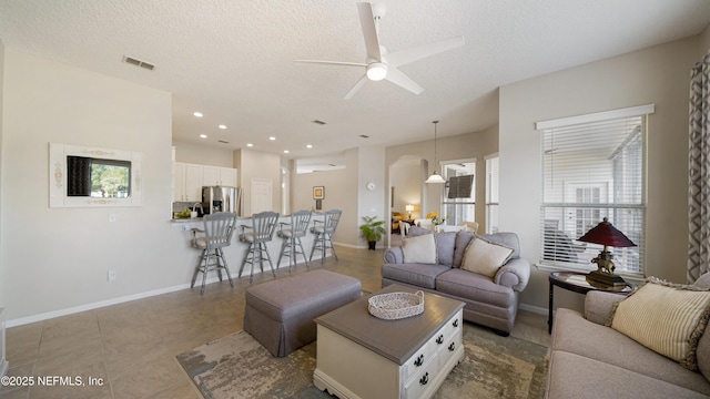 living room with ceiling fan, a textured ceiling, and light tile patterned floors