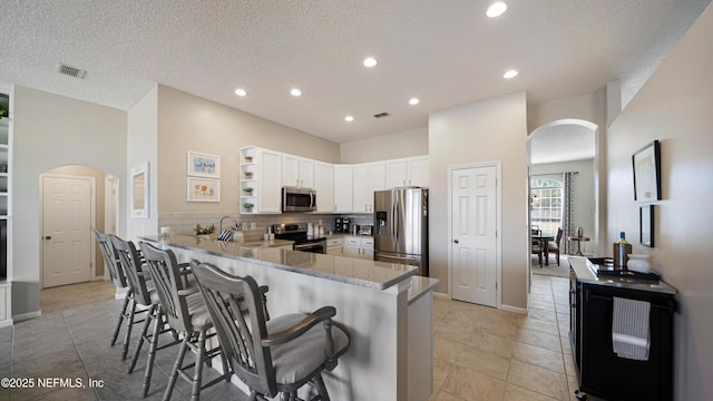 kitchen with white cabinetry, a kitchen breakfast bar, stainless steel appliances, decorative backsplash, and kitchen peninsula