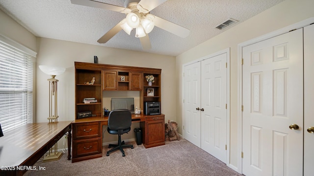 home office featuring ceiling fan, light colored carpet, and a textured ceiling