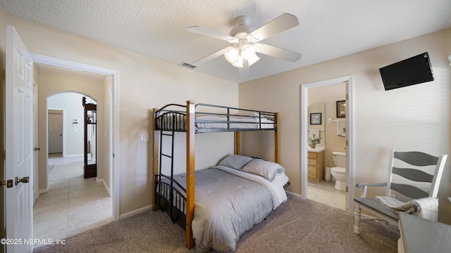 carpeted bedroom with ensuite bath and a textured ceiling