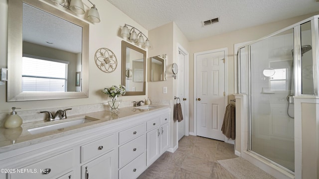 bathroom with vanity, a textured ceiling, and walk in shower