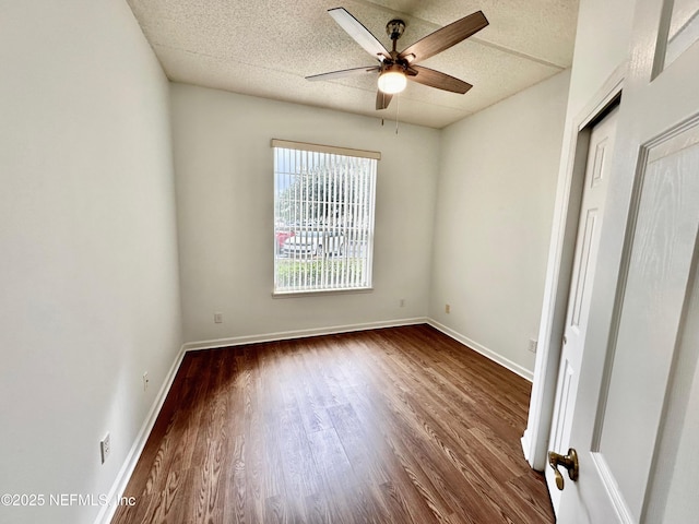 empty room with ceiling fan, dark hardwood / wood-style floors, and a textured ceiling