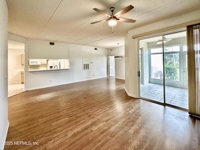 unfurnished living room featuring ceiling fan, wood-type flooring, and a textured ceiling