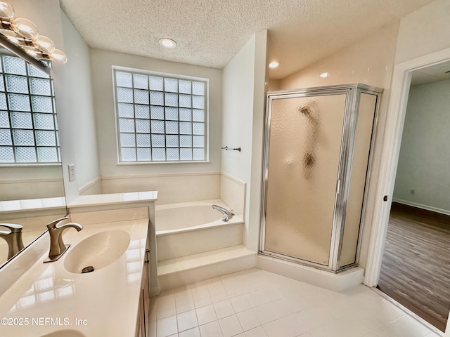 bathroom featuring vanity, a textured ceiling, shower with separate bathtub, and a healthy amount of sunlight