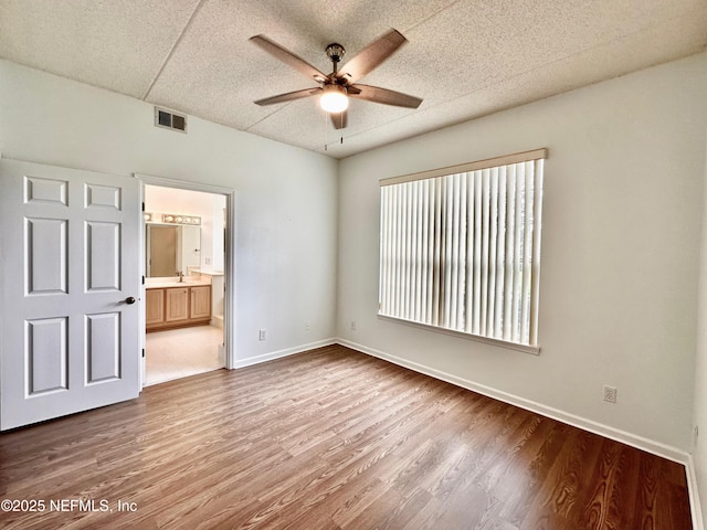 unfurnished bedroom featuring hardwood / wood-style flooring, ceiling fan, and connected bathroom