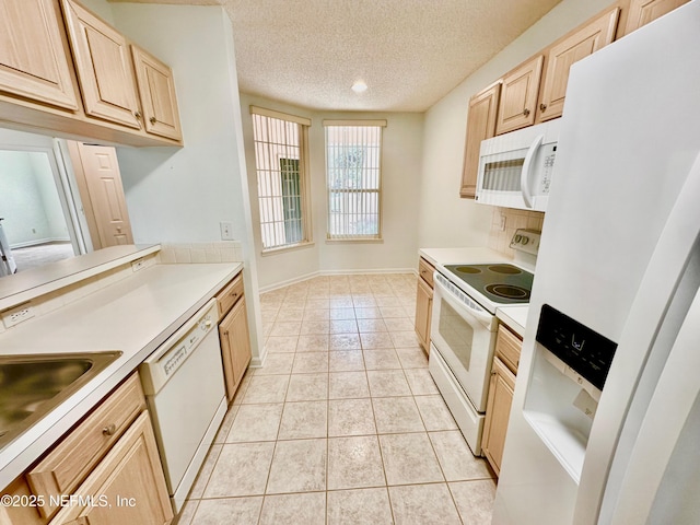 kitchen with light tile patterned floors, white appliances, sink, a textured ceiling, and light brown cabinetry