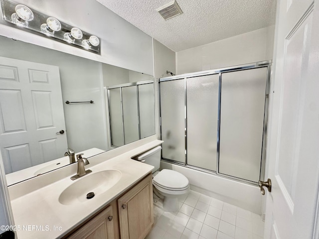 full bathroom with shower / bath combination with glass door, tile patterned flooring, vanity, toilet, and a textured ceiling