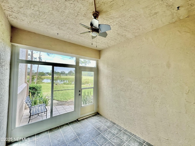 entryway featuring a water view, tile patterned floors, and ceiling fan