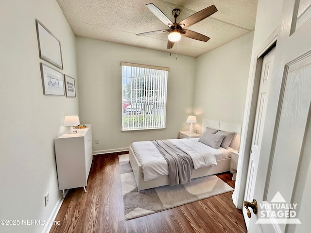 bedroom with ceiling fan, dark hardwood / wood-style flooring, and a textured ceiling