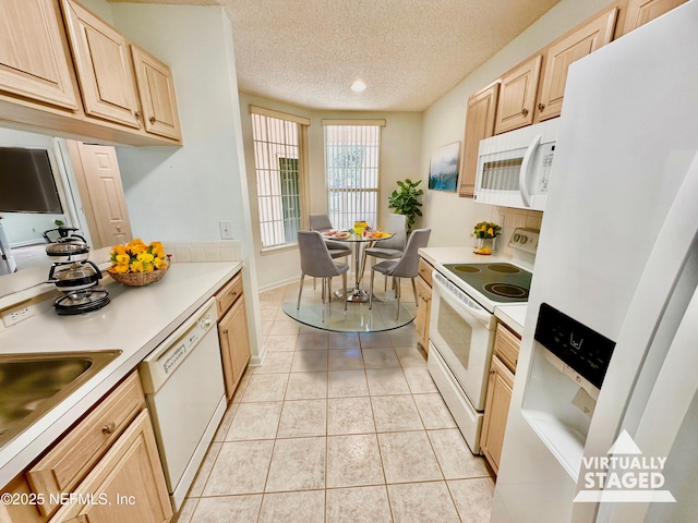 kitchen with sink, white appliances, light tile patterned floors, light brown cabinets, and a textured ceiling