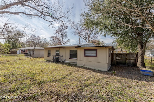 rear view of property featuring a lawn and central air condition unit