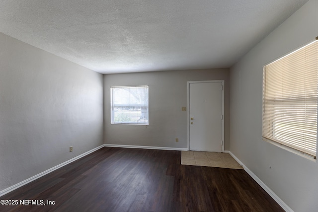 spare room featuring dark hardwood / wood-style flooring and a textured ceiling