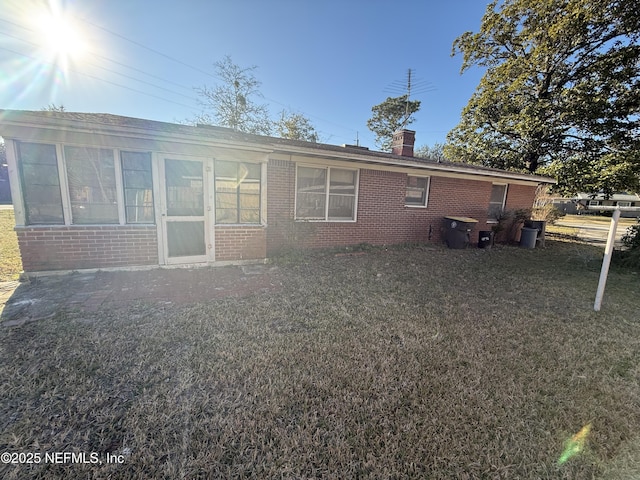 rear view of property with a lawn and a sunroom