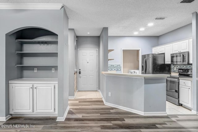 kitchen featuring visible vents, white cabinetry, light wood-style floors, light countertops, and appliances with stainless steel finishes