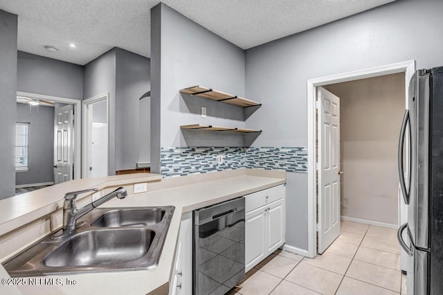 kitchen with black dishwasher, light countertops, freestanding refrigerator, white cabinets, and a sink