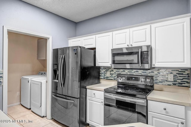 kitchen featuring appliances with stainless steel finishes, white cabinets, light countertops, and independent washer and dryer